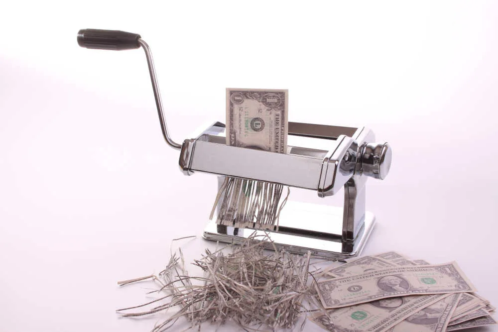 a dollar paper bill going through a paper shredder