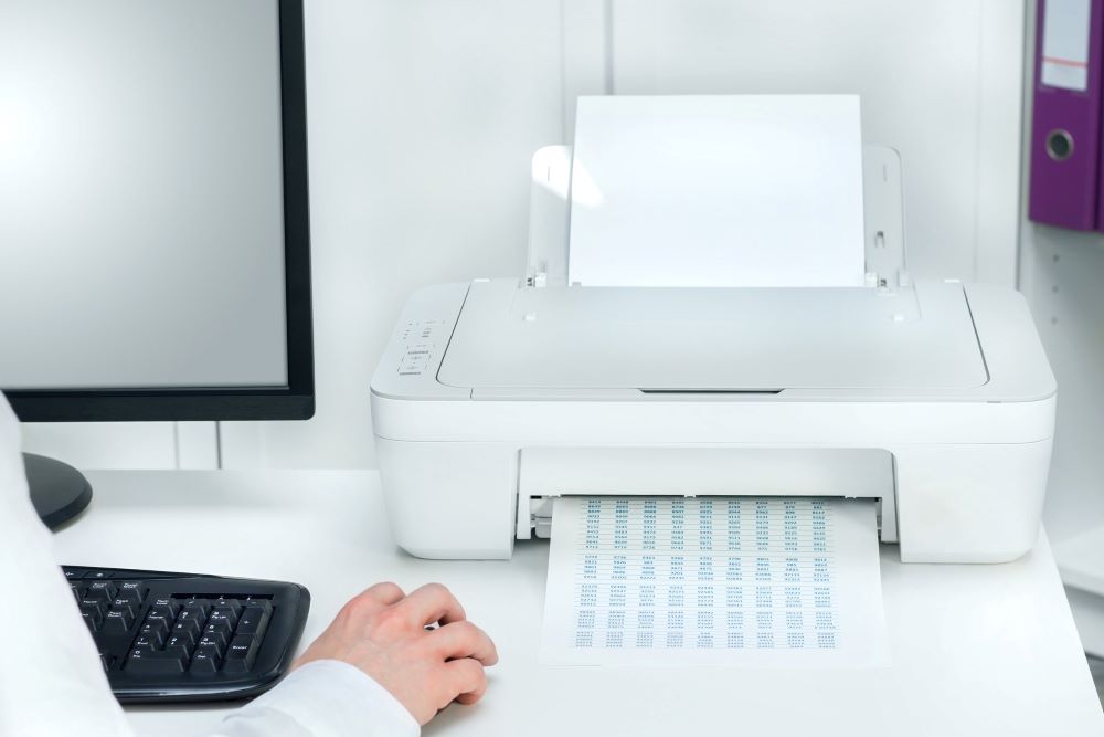 Composition of white printer and black computer in modern office