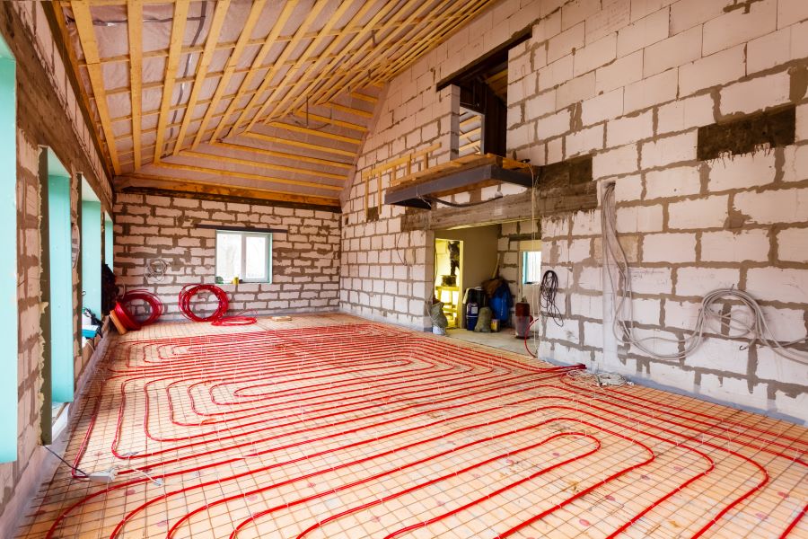 Pipefitter installing system of heating or underfloor heating installation. Water floor heating system interior.