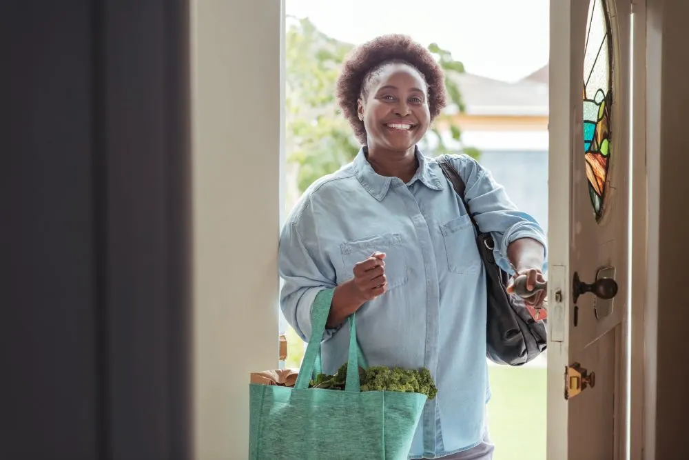 Smiling African woman arriving home from grocery shopping