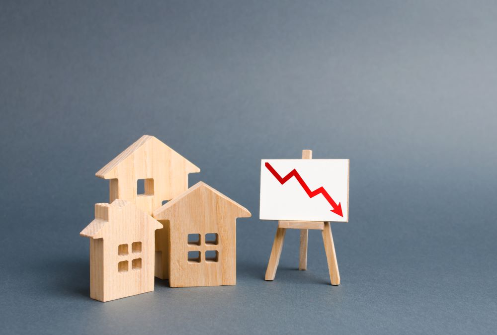  Three-wooden-houses-and-a-poster-with-a-symbol-of-declining-property-value-indicated-in-a-chart