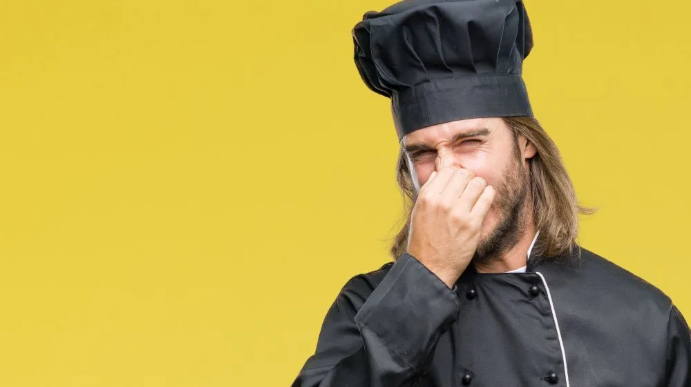 Cook with long hair over pinching his nose
