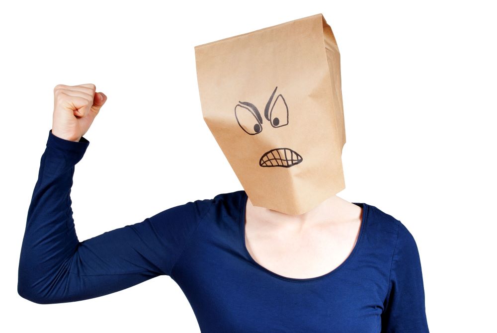 person wearing a brown paper bag with a drawing of an angry face