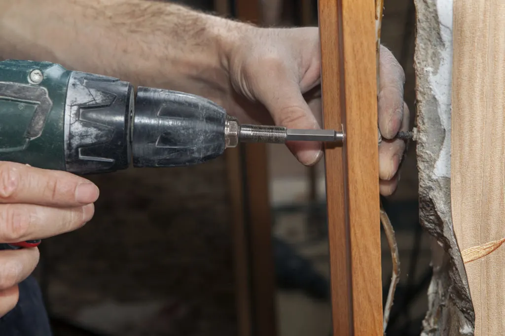 Carpenter fix jamb in doorway using a cordless drill electric screwdriver