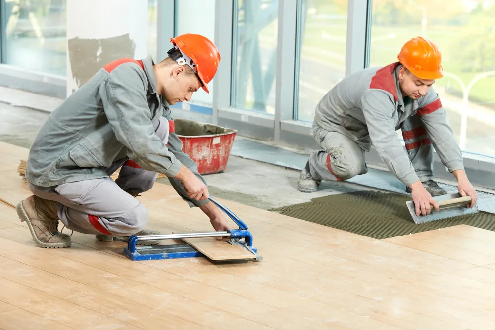 Two industrial tiler builder worker installing floor tile at repair renovation work fix floors handyman