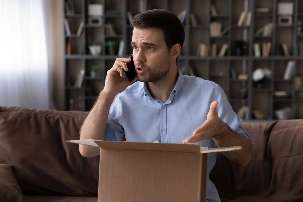 Unhappy angry Caucasian male client or buyer talk with customer service on cellphone frustrated by delivery mistake or error. Mad man have fight with shipping company dissatisfied with bad service.