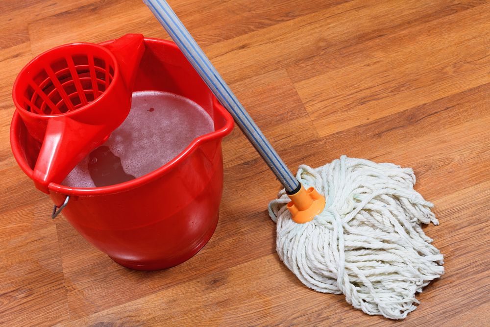 cleaning of floors by mop and red bucket with washing water