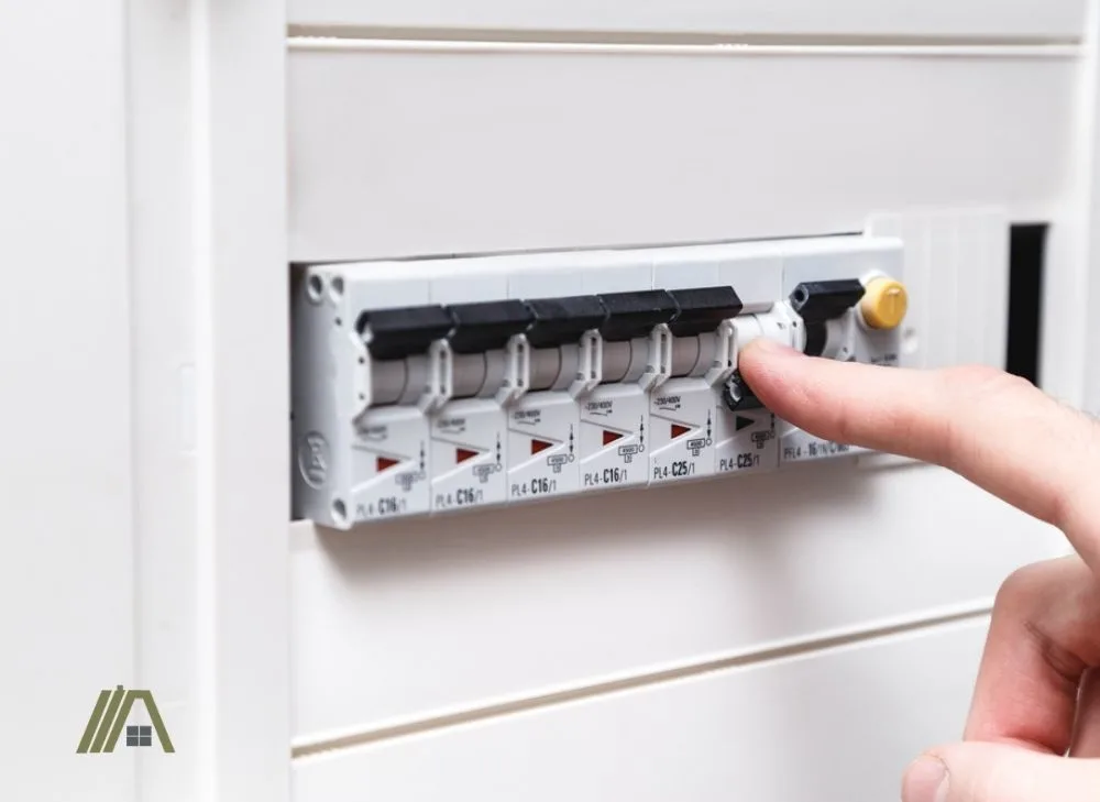 Man's hand turning off circuit breaker with many switch