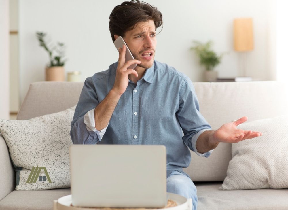 Unsatisfied Guy Complaining About Problems With Laptop By Phone Indoor