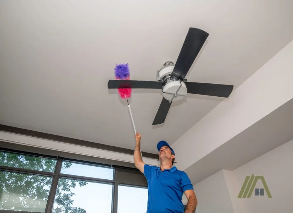 Cleaning the dust of a black ceiling fan