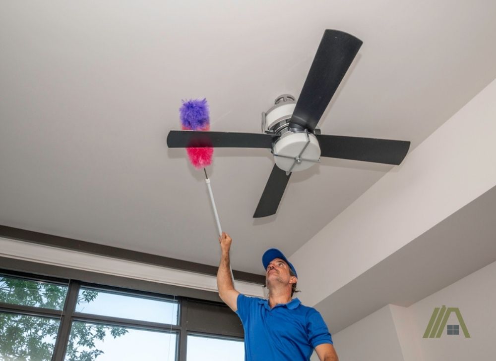 Man cleaning and dusting off the ceiling fan