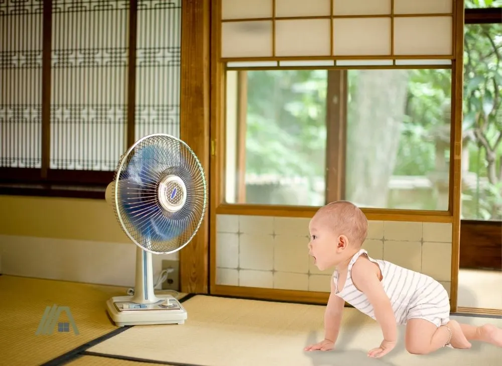 baby crawling near a fan