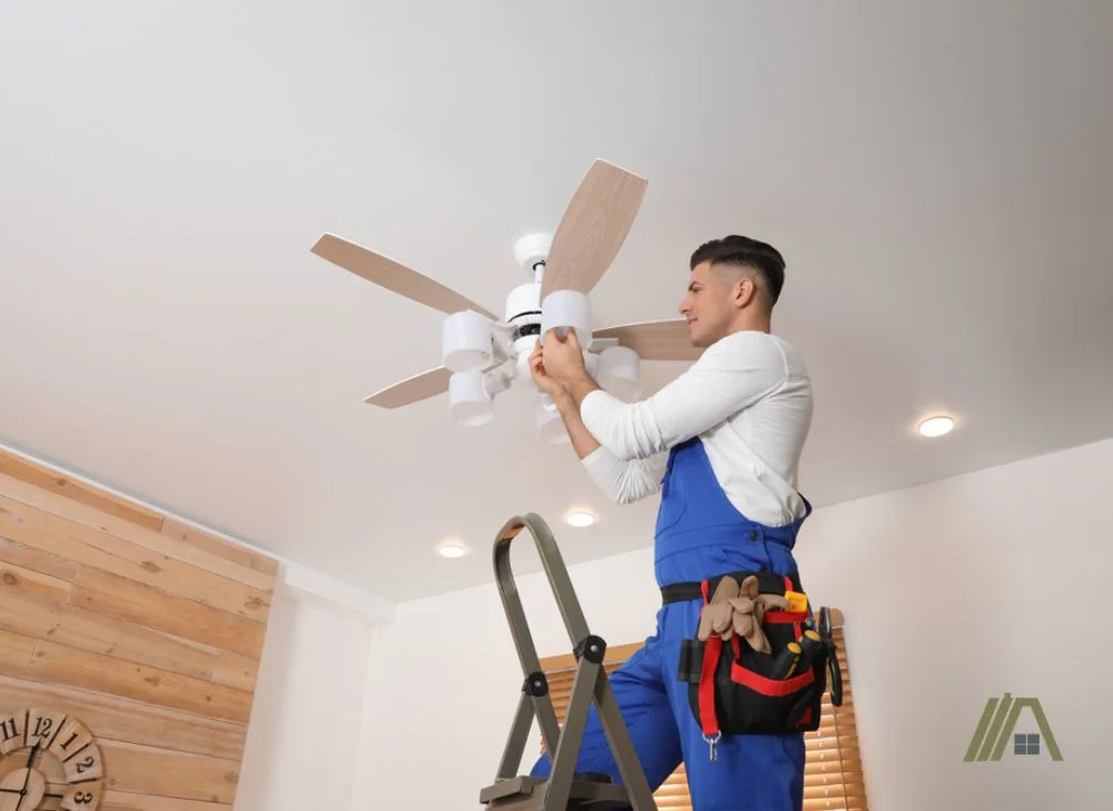 man checking the light bulb of the ceiling fan