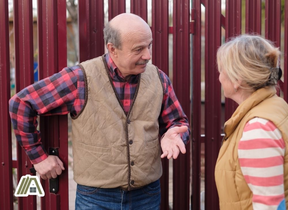 senior man talking to a senior woman about their fence