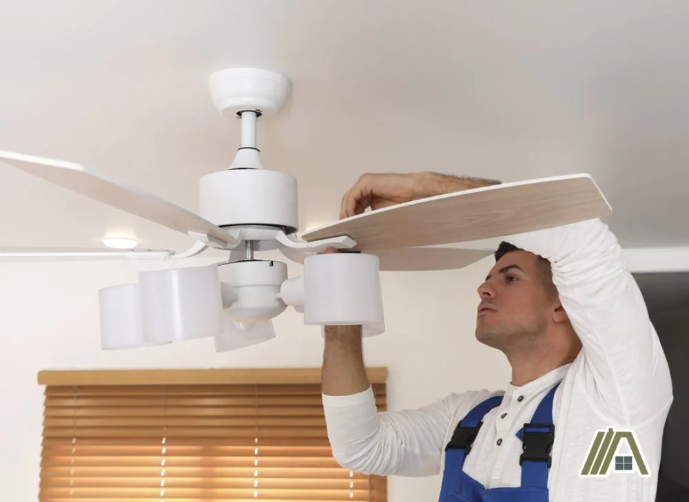 Man inspecting the white ceiling fan with lights
