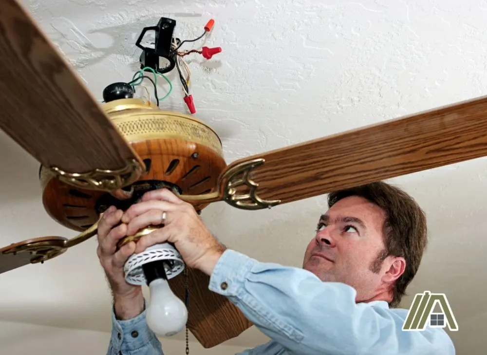 Man inspecting the wiring of a ceiling fan