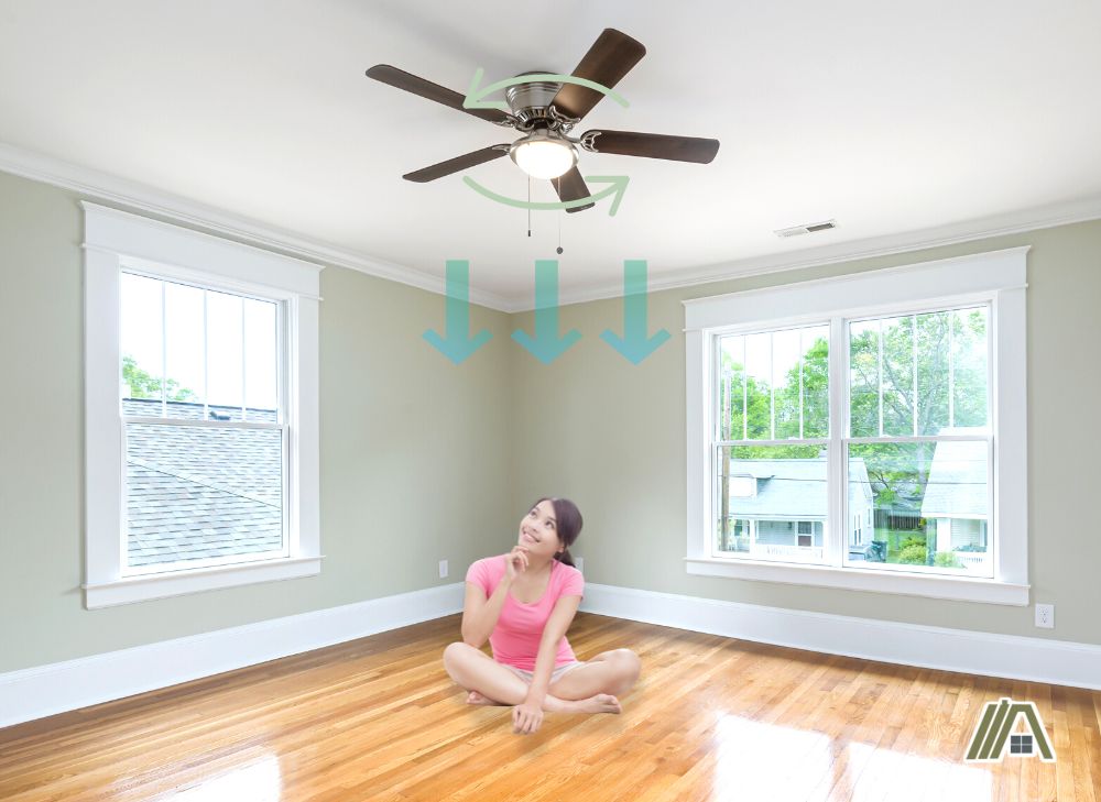 Girl sitting on floor with a ceiling fan rotating clockwise pushing air downward