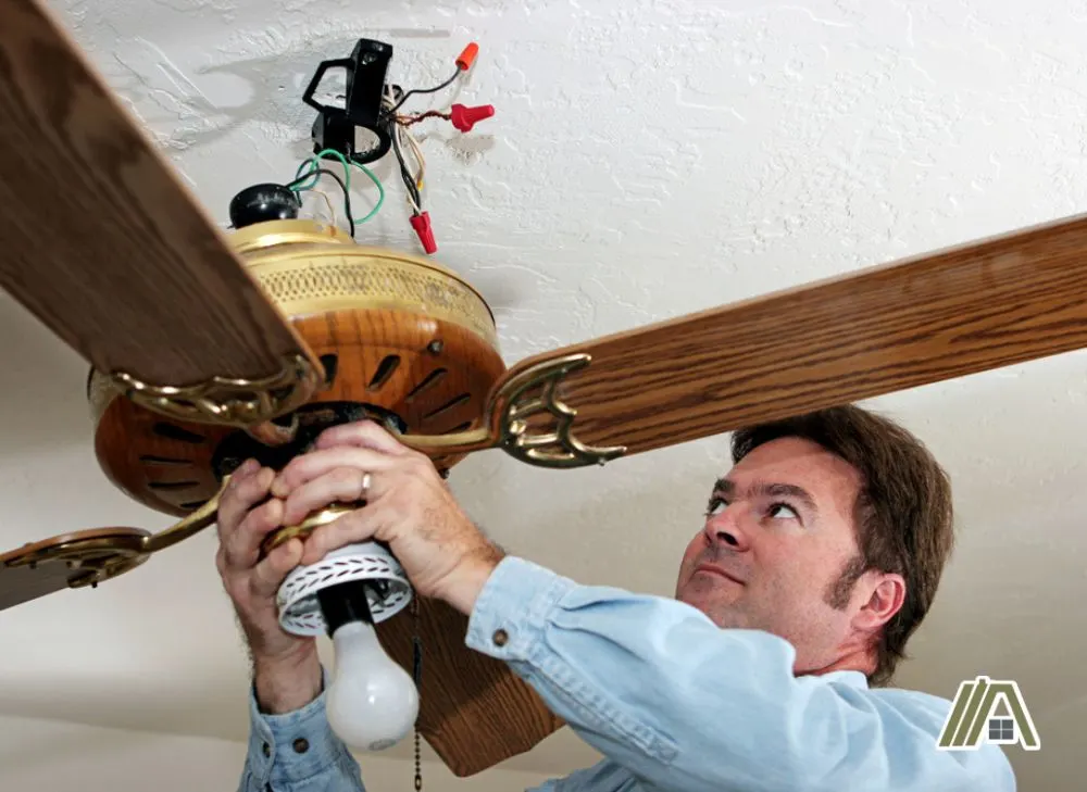 Man checking the wiring of a ceiling fan