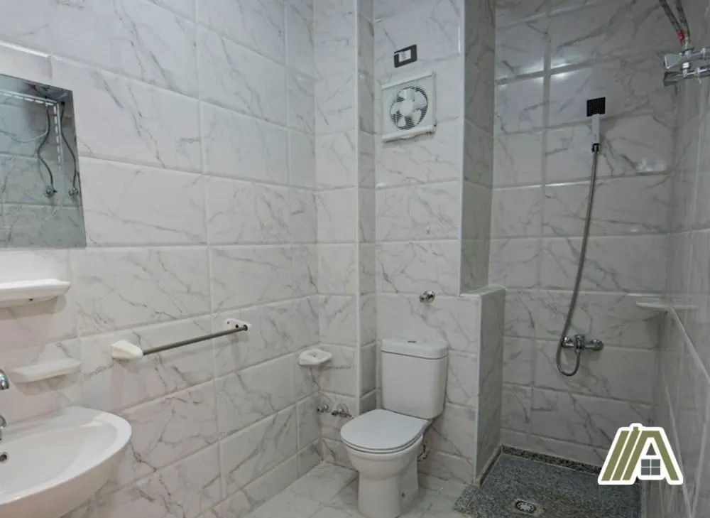 Bathroom exhaust installed in a wall full of white tiles
