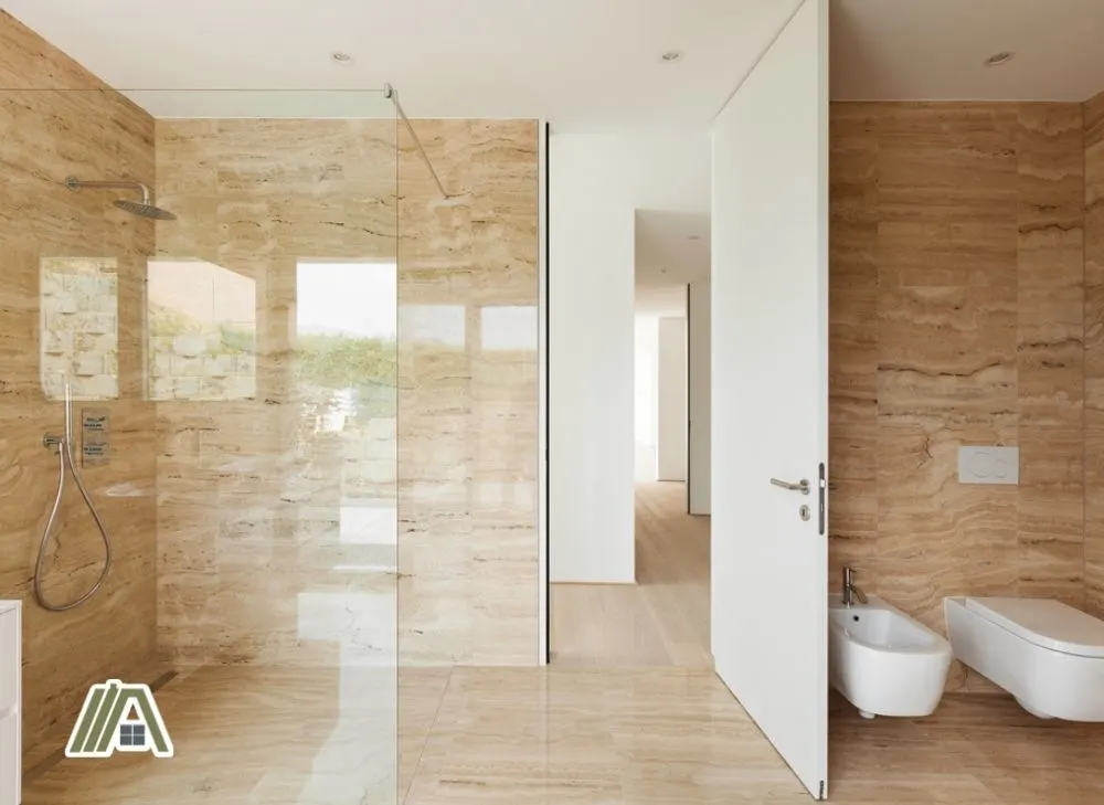 Modern bathroom with marble tiles on walls and an open white door