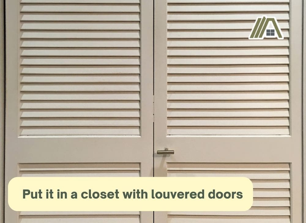 Put it in a closet with louvered doors, white closet with louvered doors