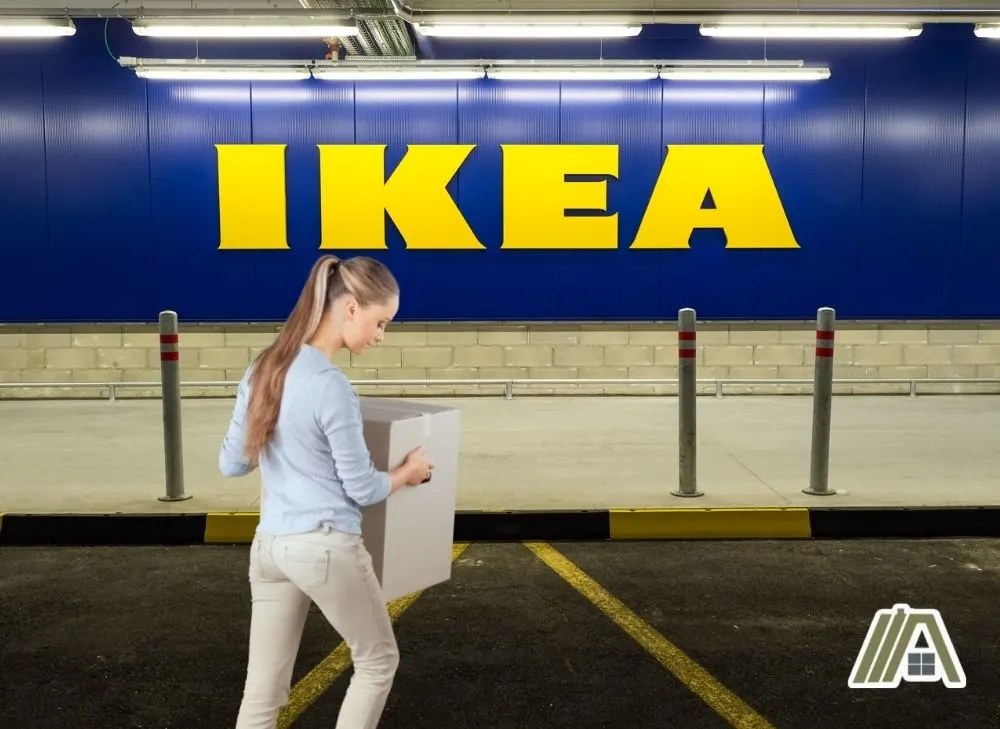 Woman wearing a blue long sleeves carrying an unopened box and returning it to IKEA