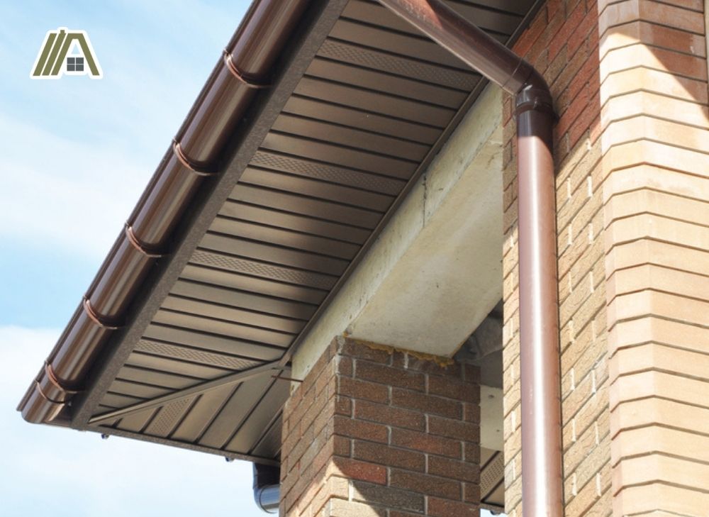 Drain installed on fascia with brown eaves and column with brick façade