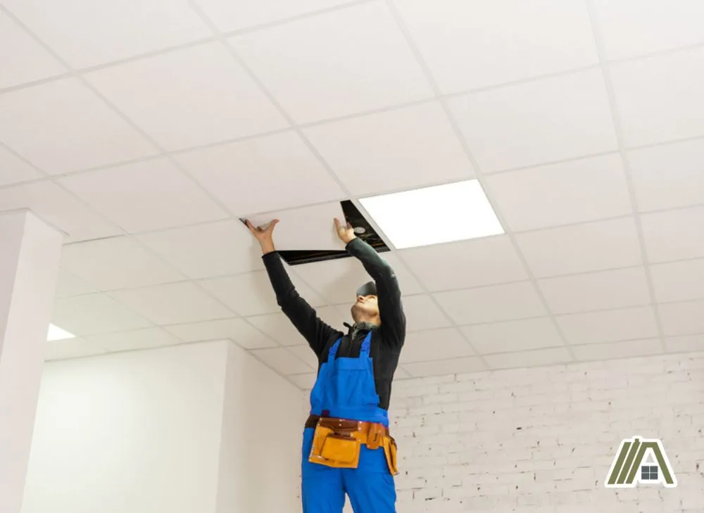 Handyman installing white drop ceiling tiles