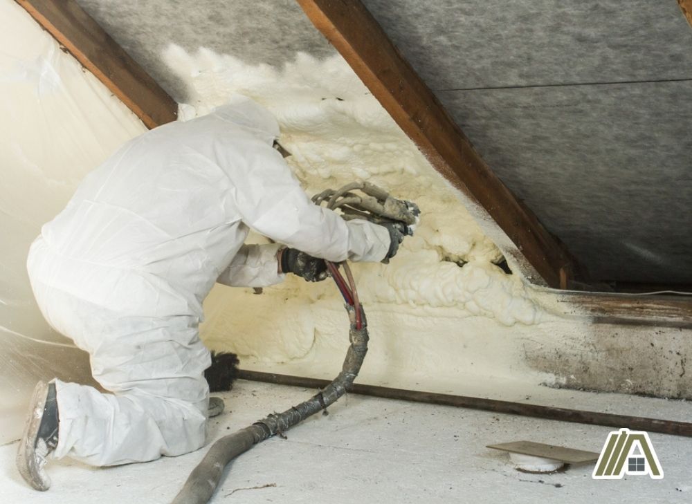 Man wearing white full PPE while spraying foam insulation on the attic