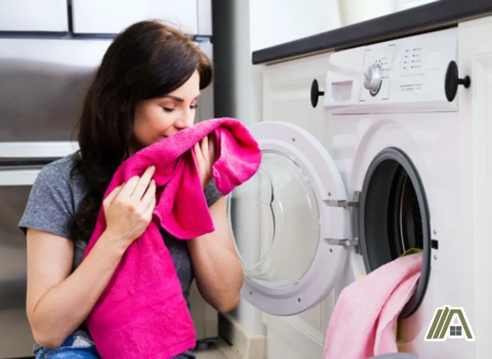 Woman smelling a fuchsia colored towel from the laundry machine