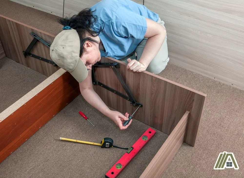 Woman wearing a hat while screwing the steel support for a wooden table