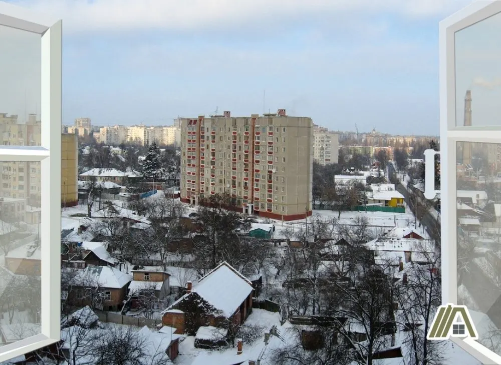 Open window to the city on winter season, buildings and houses filled with snow