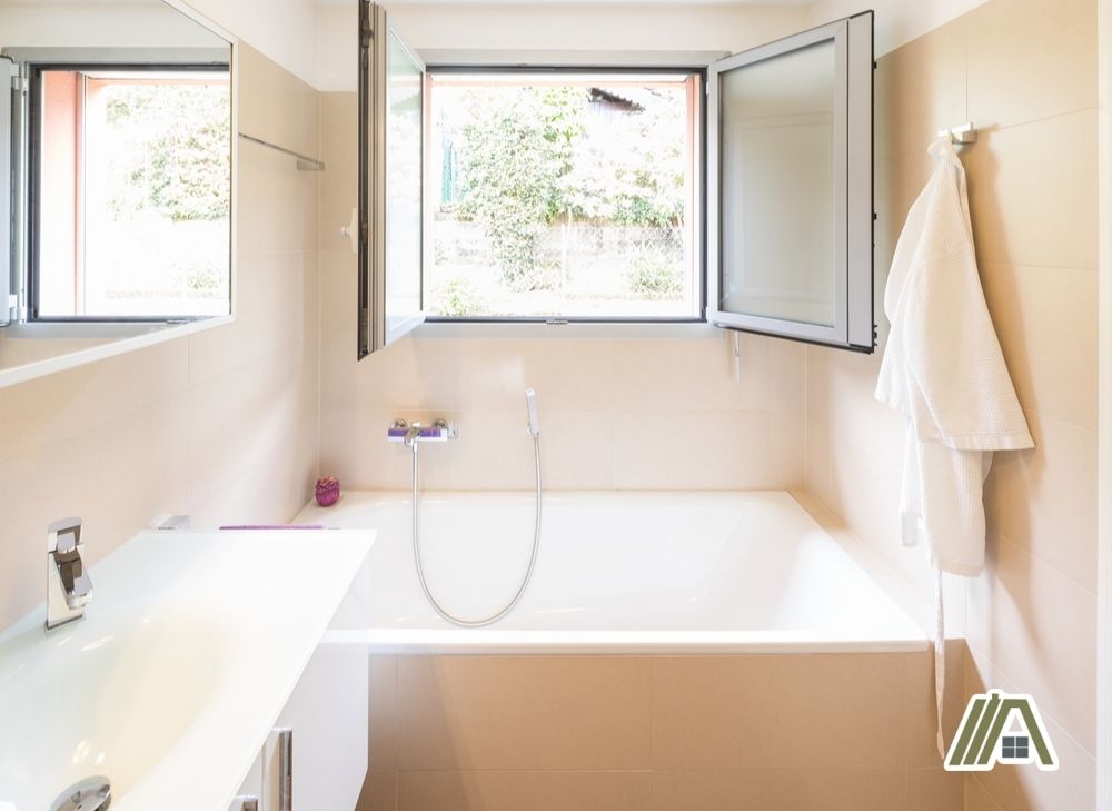 Bright cream colored bathroom with bathtub and open square window