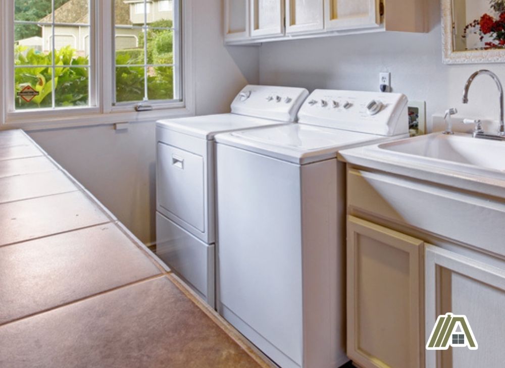 Gas dryer and a washing machine inside the laundry room with windows and faucet