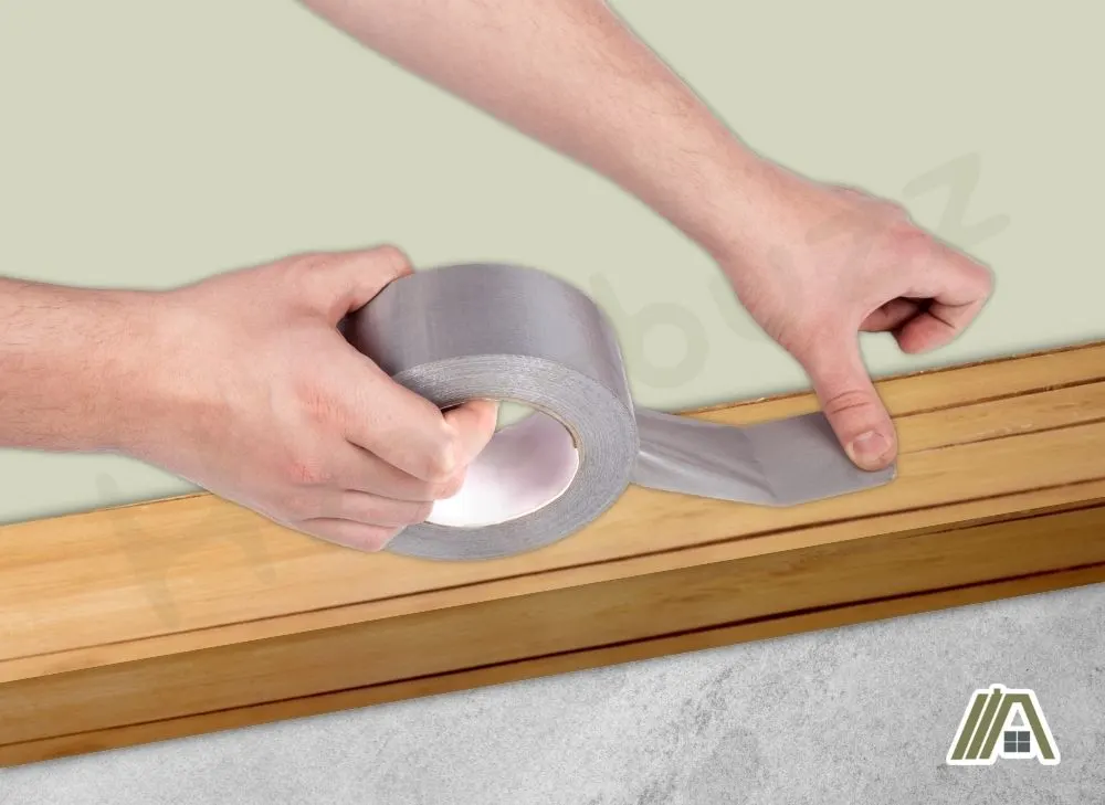 Man putting duct tape on wood plank