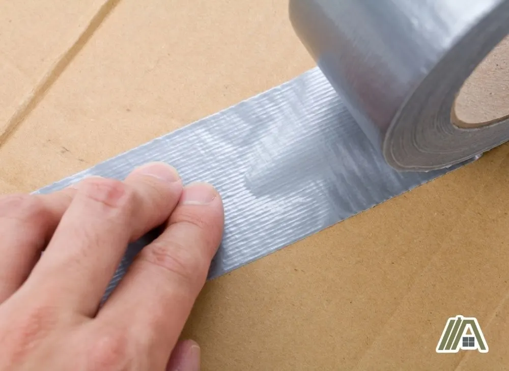 Man-sticking-duct-tape-into-a-cardboard