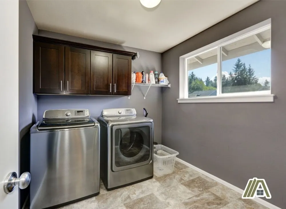 Mega capacity dryer and washer inside a laundry room with gray walls and a window