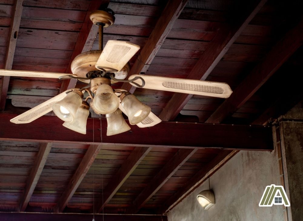 Old vintage ceiling fan with lamp light installed in a wooden ceiling