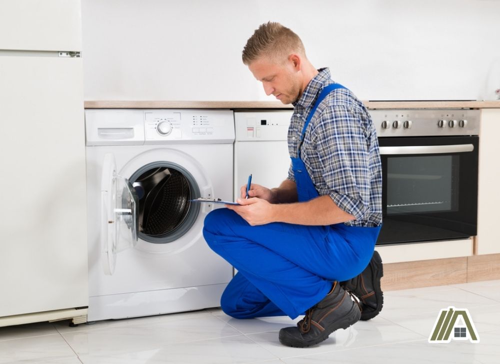 Electrician or repair man checking the washing machine and a the dryer at home