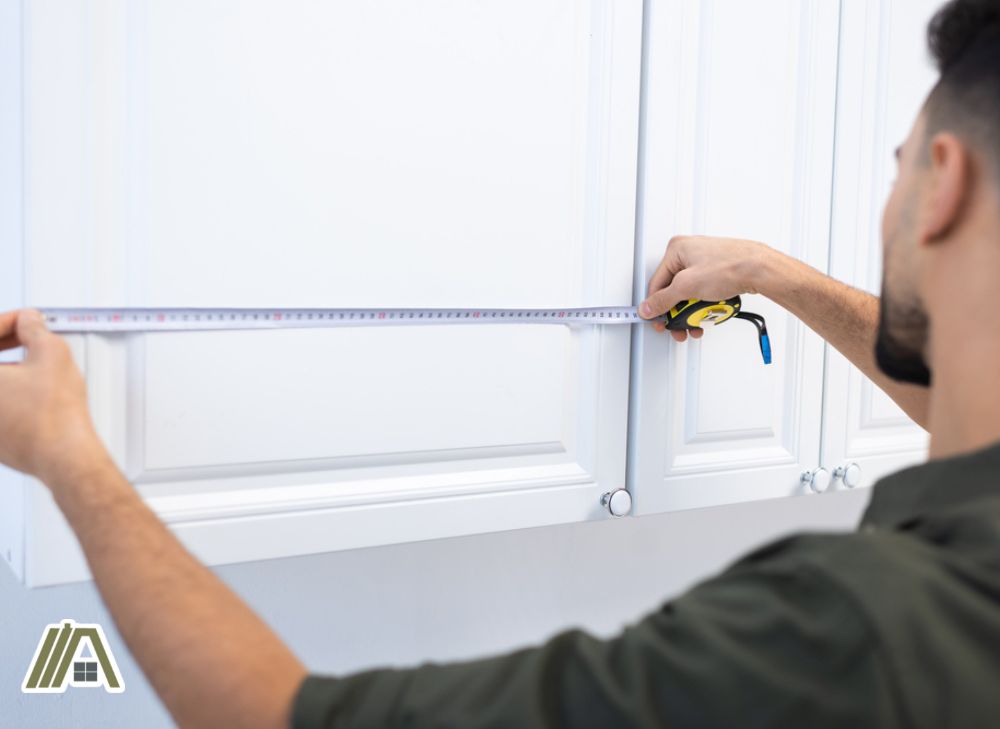 Man measuring a cabinet using a measuring steel tape