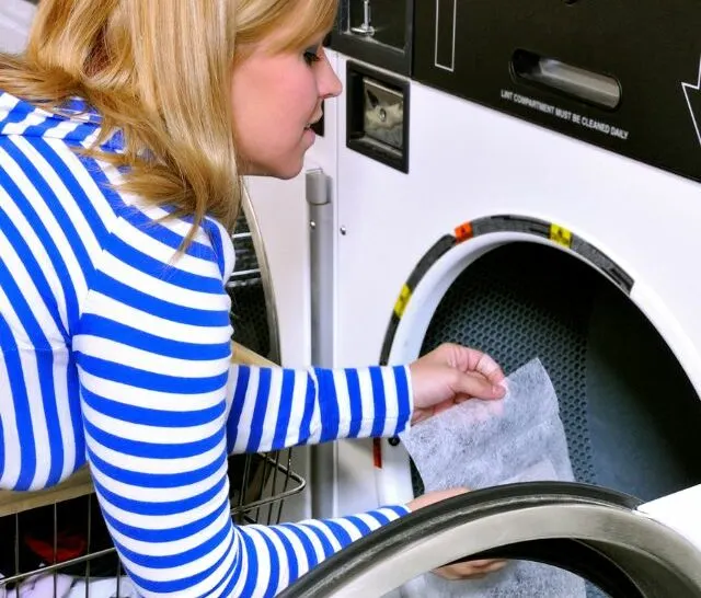 Woman putting dryer sheet inside the dryer