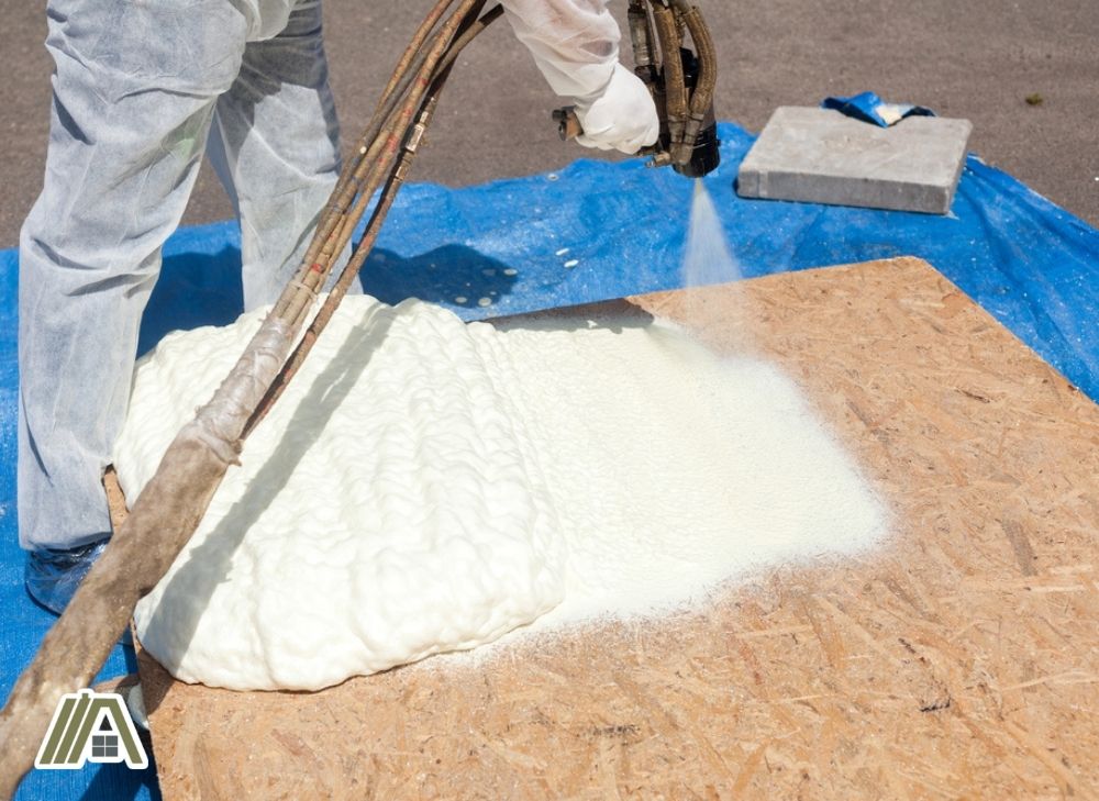 Man in PPE spraying spray foam insulation on a wood panel.jpg