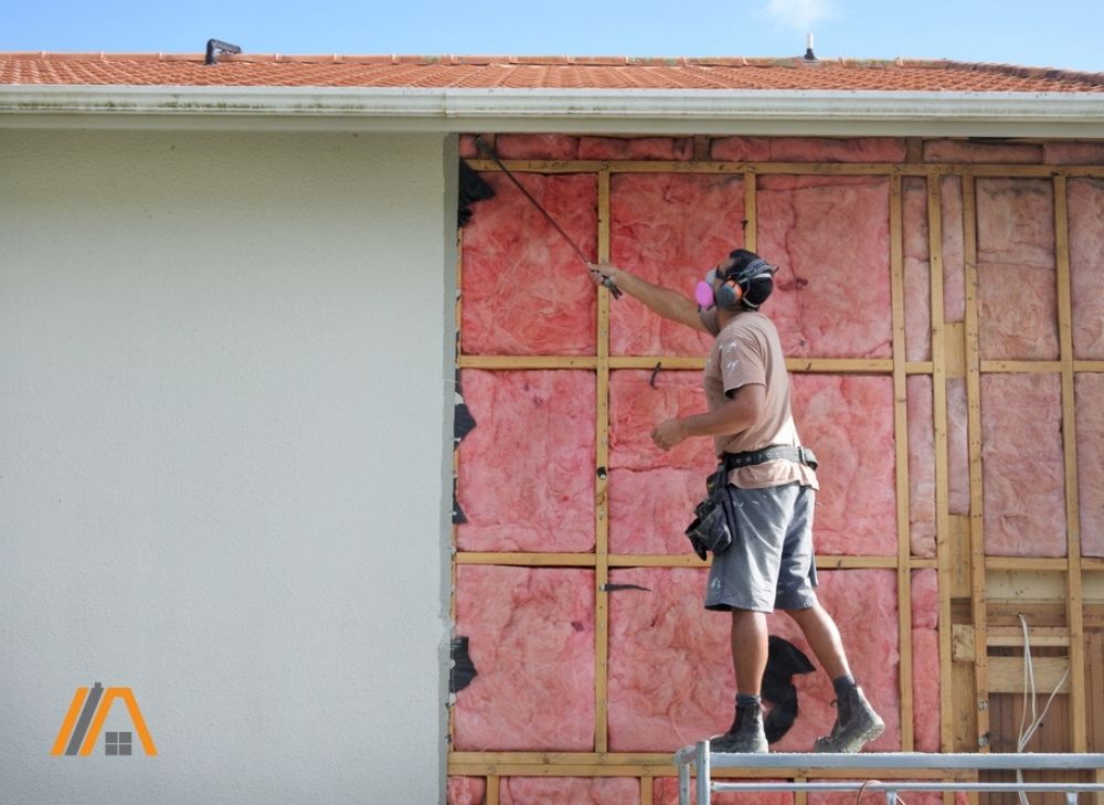 Man removing exterior pink insulation of a house