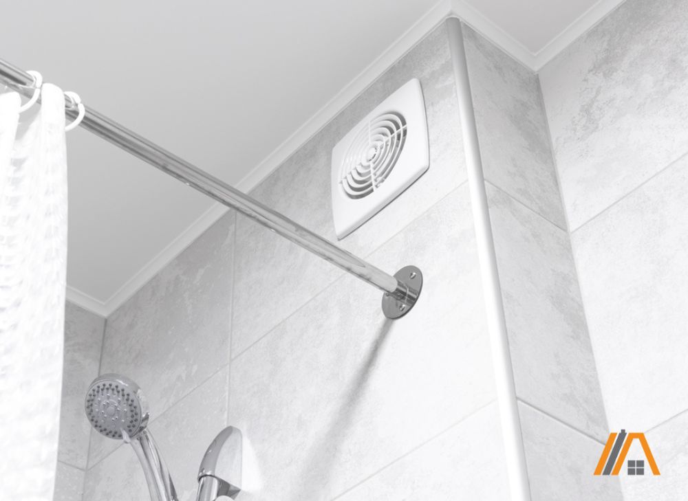 Bathroom exhaust fan installed on a wall with gray tiles