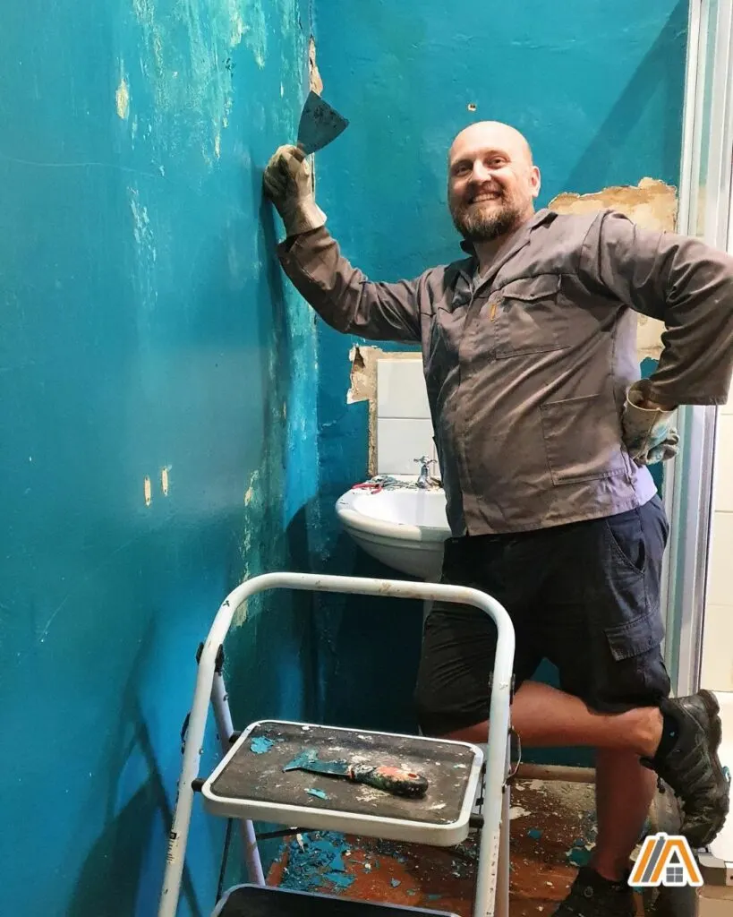 Man removing turquoise bathroom paint