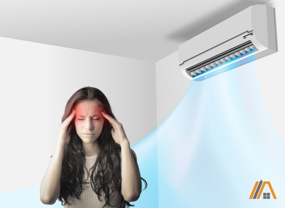 Woman standing directly under an air-conditioning unit with a headache