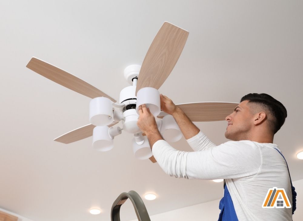Man placing light inside the wooden ceiling fan with light