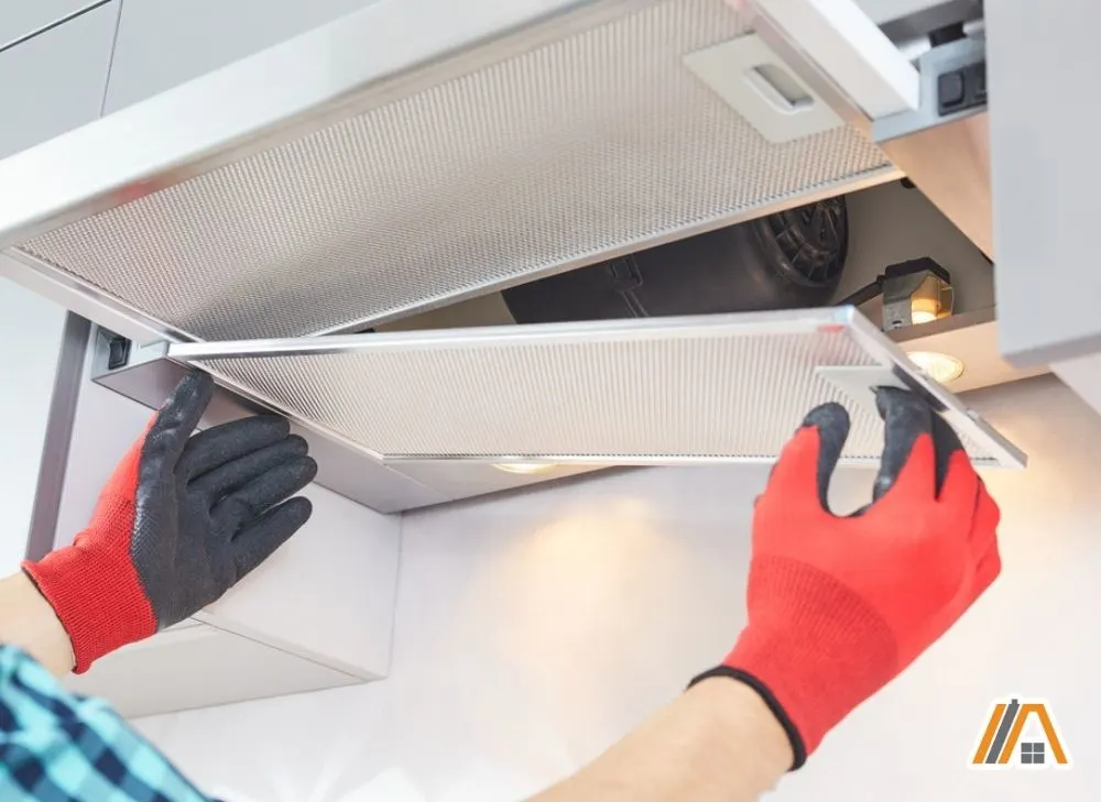 Man wearing gloves removing the grease filter of range hood