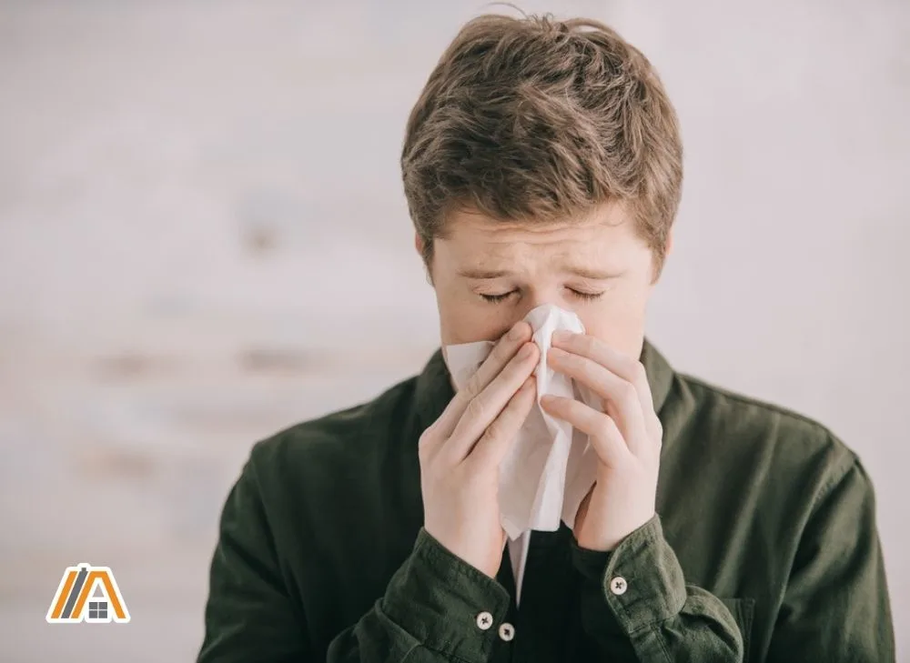 Man wearing long sleeves sneezing due to allergy