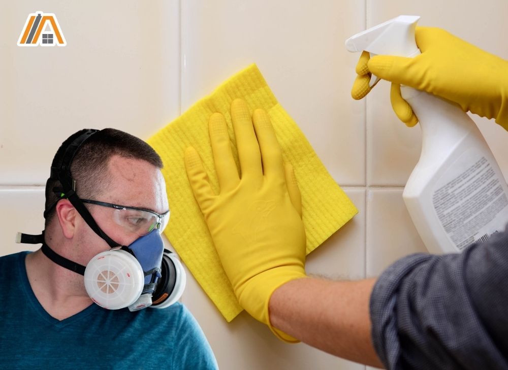 Man wearing paint protective mask and man cleaning bathroom tiles using a sponge and bleach.jpg